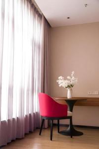 une chaise rouge assise à côté d'une table avec un vase de fleurs dans l'établissement Borrman Hotel Baise High-speed Railway Station Hengning Plaza, à Baise