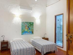 two beds in a room with a painting on the wall at Casa Digna in Cartagena de Indias