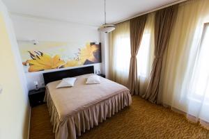 1 dormitorio con 1 cama y una pintura en la pared en Hotel Grandis Apulum, en Mioveni