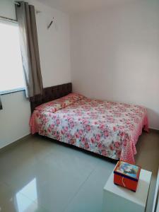 a small bedroom with a bed with a red blanket and a table at Colares House Pedra de Guaratiba - 2 quartos - style and comfort in Pedra de Guaratiba