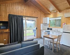 a living room with a couch and a table and a kitchen at Maydena Mountain Cabins in Maydena