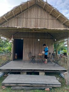 a person standing on a porch of a hut at Eco Camping - Bamboo House in Can Gio