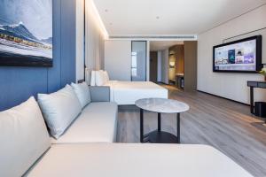 une chambre d'hôtel avec deux lits et une télévision dans l'établissement Atour Hotel Yantai Bajiaowan University Town, à Yantai