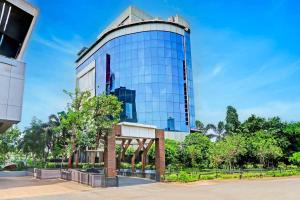 Un edificio alto de cristal con árboles delante. en Palette Hotel and Resort Zero Mile Sitabuldi Formerly Gangakashi, en Nagpur