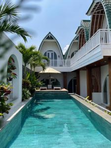a swimming pool in front of a villa at Jasmine River Guest House in Canggu