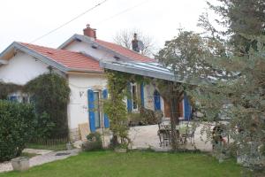 ein weißes Haus mit blauen Fenstern und einem Hof in der Unterkunft Le Tacot in Auxon-Dessus