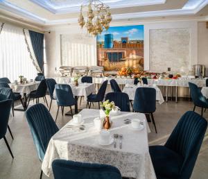 Un restaurante con mesas y sillas y una pantalla de proyección. en Hotel FAROHAT ONA, en Khiva