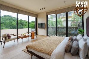 Un dormitorio con una cama grande y grandes ventanales. en StayVista at Cielo House with Bonfire, Pool, en Alibaug