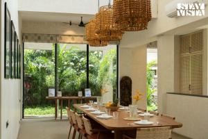 Un comedor con una mesa larga y sillas. en StayVista at Cielo House with Bonfire, Pool, en Alibaug