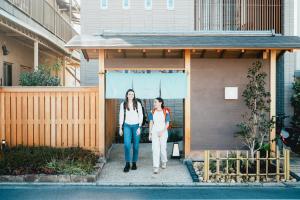 広島市にあるLAZULI Hiroshima Hotel and Loungeの家の前を歩く二人