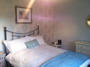 a bedroom with a white bed with a blue blanket at East Dunster Deer Farm B&B in Tiverton