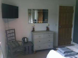 a bedroom with a dresser and a mirror and a chair at East Dunster Deer Farm B&B in Tiverton