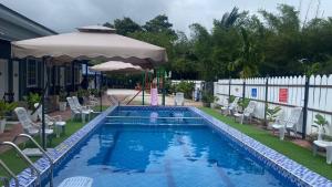 piscina con ombrellone e sedie e ombrellone di Capital O 91205 Palong Hill Chalet & Resort a Baling