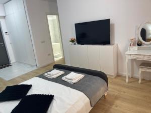 a living room with a tv and a bed with towels at Modern Studio With Balcony - Unirea Towers Iasi in Iaşi