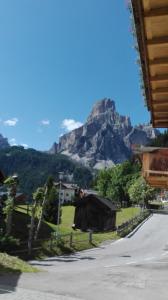 Une montagne au loin avec une maison et une route dans l'établissement Pensione Valbona, à Corvara in Badia