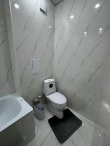 Un baño blanco con inodoro y lavabo. en Апартамент, en Uralsk