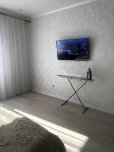 Una habitación con una mesa y un televisor en la pared. en Апартамент, en Uralsk