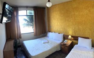 een hotelkamer met 2 bedden en een televisie bij Hotel Bellatrix in Macaé