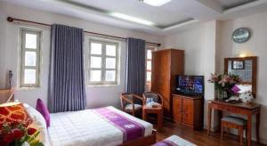 a bedroom with a bed and a desk and windows at Hồng Hạc hotel in Ho Chi Minh City