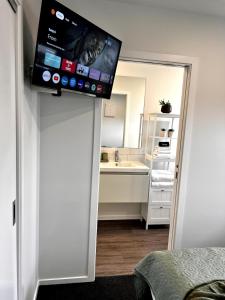 a bathroom with a sink and a tv on the wall at Queenstown Studio with Mountain Views in Frankton