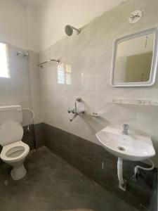 ブバネーシュワルにあるAtithi Darbarの白いトイレと洗面台のあるバスルーム +9枚の写真
