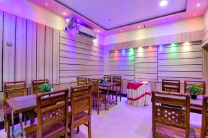 a dining room with tables and chairs and purple lights at Hotel O Mahal in Durgāpur