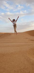 una mujer saltando en la arena en el desierto en Arabian Desert nights, en Badīyah