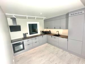 una grande cucina con mobili bianchi e pavimento in legno di Kaldfjord Aurora Apartments New Top floor a Tromsø