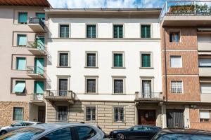 un grande edificio bianco con le auto parcheggiate di fronte di Casa Alessandro a Firenze