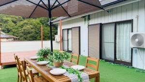 a wooden table with plants and an umbrella on a patio at KeiCo in Narusawa