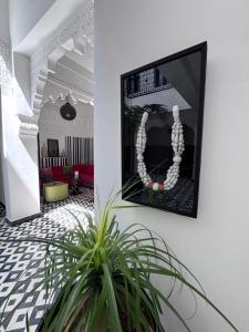 a picture hanging on a wall with a plant at Riad Looma in Marrakesh