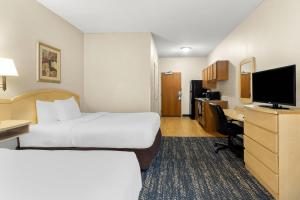a hotel room with two beds and a desk at Suburban Studios Morgantown in Morgantown