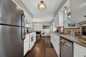Una cocina con gabinetes blancos y un refrigerador de acero inoxidable. en Cora Street Cottage, en Fredericksburg