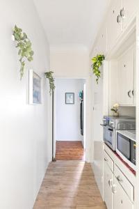 kuchnia z białymi szafkami i drewnianą podłogą w obiekcie No Frill Affordable Single Room - Seconds to Transport & Shops - Shared Bathroom w mieście Killara