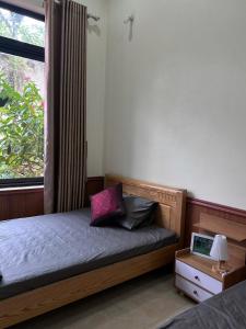 ein Schlafzimmer mit einem Holzbett mit Fenster in der Unterkunft Mellowmoo Homestay in Nguyễn Thôn