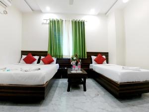 two beds in a room with green curtains at Hotel Sai SK Palace in Shirdi