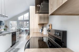 a kitchen with wooden cabinets and a black appliance at Ski Mont Saint-Anne - Absolute Comfort - Mont Lumina in Beaupré