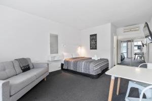 a bedroom with a bed and a couch and a table at Comfort Inn Commodore Albury in Albury