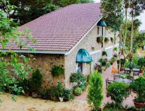 une maison en pierre au toit rouge avec des plantes dans l'établissement Dalat Train Village, à Đà Lạt
