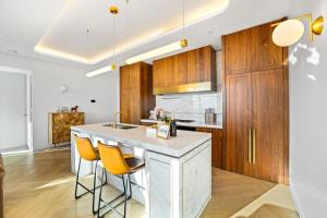 Highrise Luxury Penthouse with City Ocean Mountain View في بوكسهل: مطبخ بخزائن خشبية وجزيرة بيضاء مع كراسي صفراء