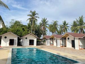 a villa with a swimming pool and palm trees at โรงแรมสบายดีรีสอร์ท in Tha Bo