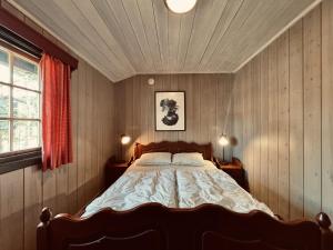 a bedroom with a large bed in a room with wooden walls at Briskebu, cosy cabin by ski slopes in Geilo