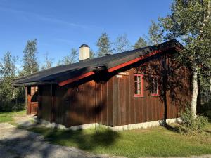 a small wooden cabin with a black roof at Briskebu, cosy cabin by ski slopes in Geilo