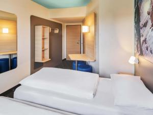 a room with two beds and a desk at B&B Hotel Darmstadt in Darmstadt +18 photos