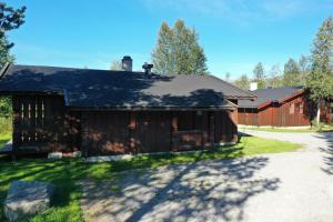 a brown barn with a driveway next to a house at Tvilsombu, cosy cabin close to ski slopes in Geilo
