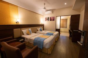 a hotel room with two beds and a chair at Hotel High Point in Tiruchchirāppalli +53 photos