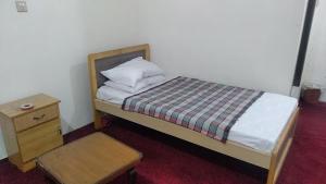 a small bedroom with a bed and a night stand at RC Hotel in Dargai +4 photos