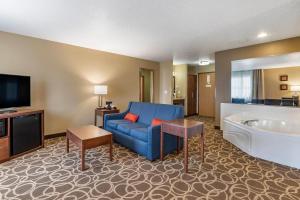 a hotel room with a blue couch and a tub at Comfort Inn Dyersville Near the Field of Dreams in Dyersville
