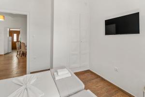 a white room with a bed and a flat screen tv at Chora Sea Nest, 2-BDR Flat in Andros Town in Andros