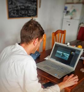 einem Mann, der an einem Tisch mit einem Laptop sitzt in der Unterkunft Famara home Stay 1 in Famara